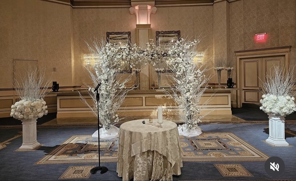 Winter white branch and blossom arch framing the unity table in a gold ballroom