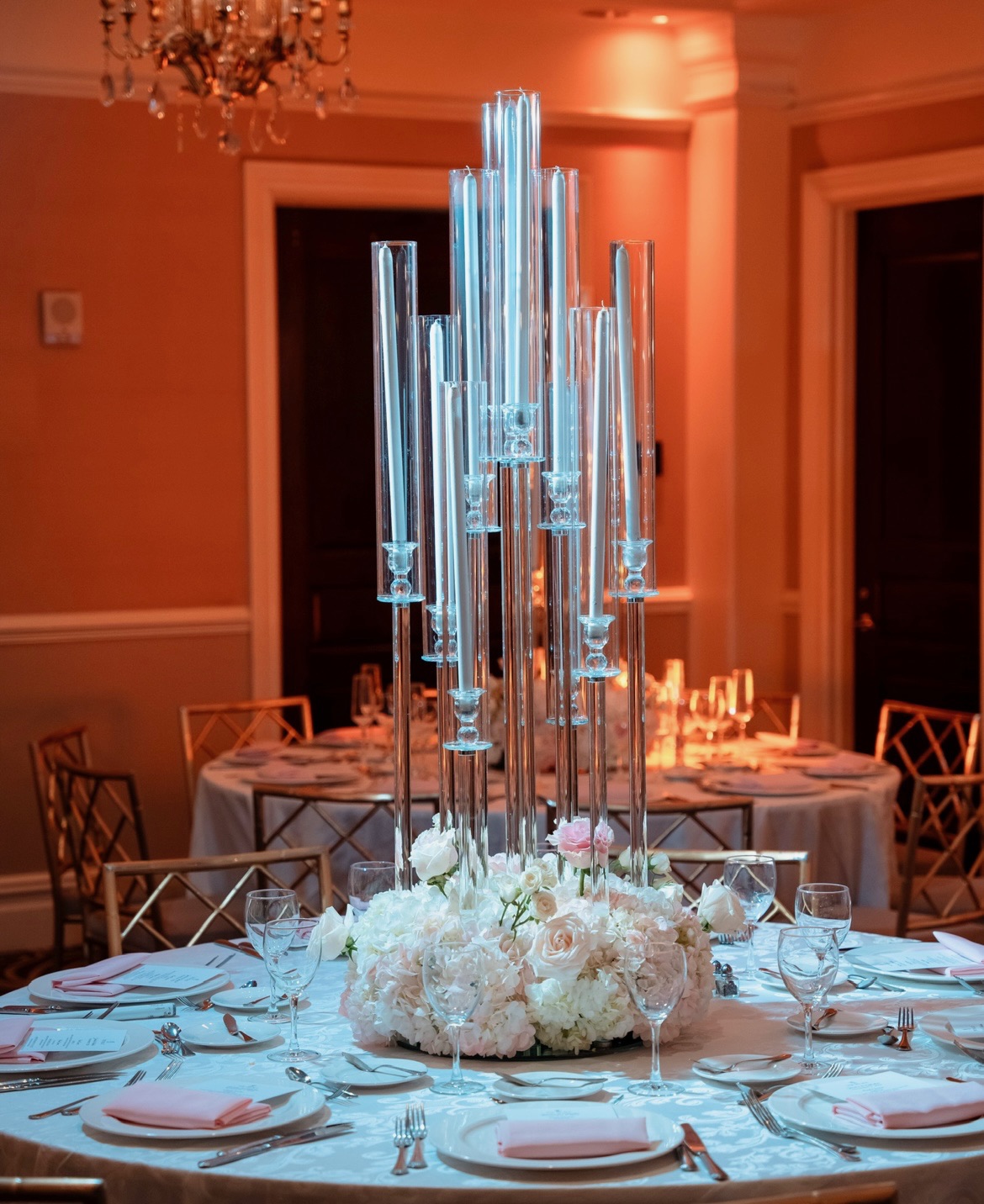 Tall crystal candelabra above a lush dome of white and blush roses and hydrangea