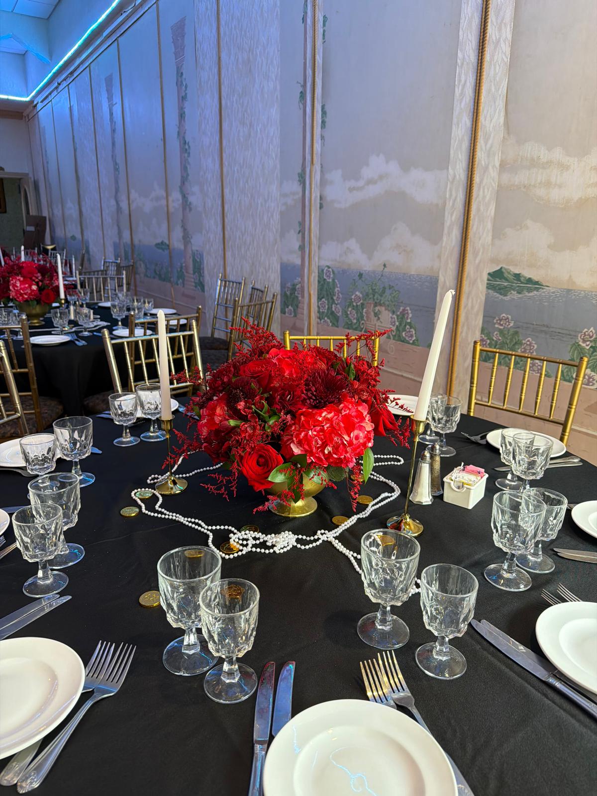 Gatsby-style table with a gold compote of red hydrangea, roses and celosia, pearl strands and tall tapers