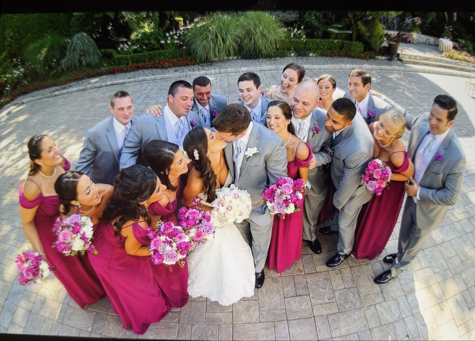Bridal party gathered around the couple, bridesmaids in berry gowns holding fuchsia and lavender rose bouquets