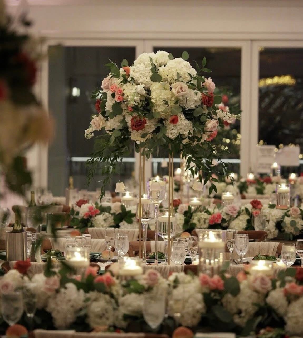 Tall white hydrangea and blush rose centerpiece on a gold stand with hanging votives