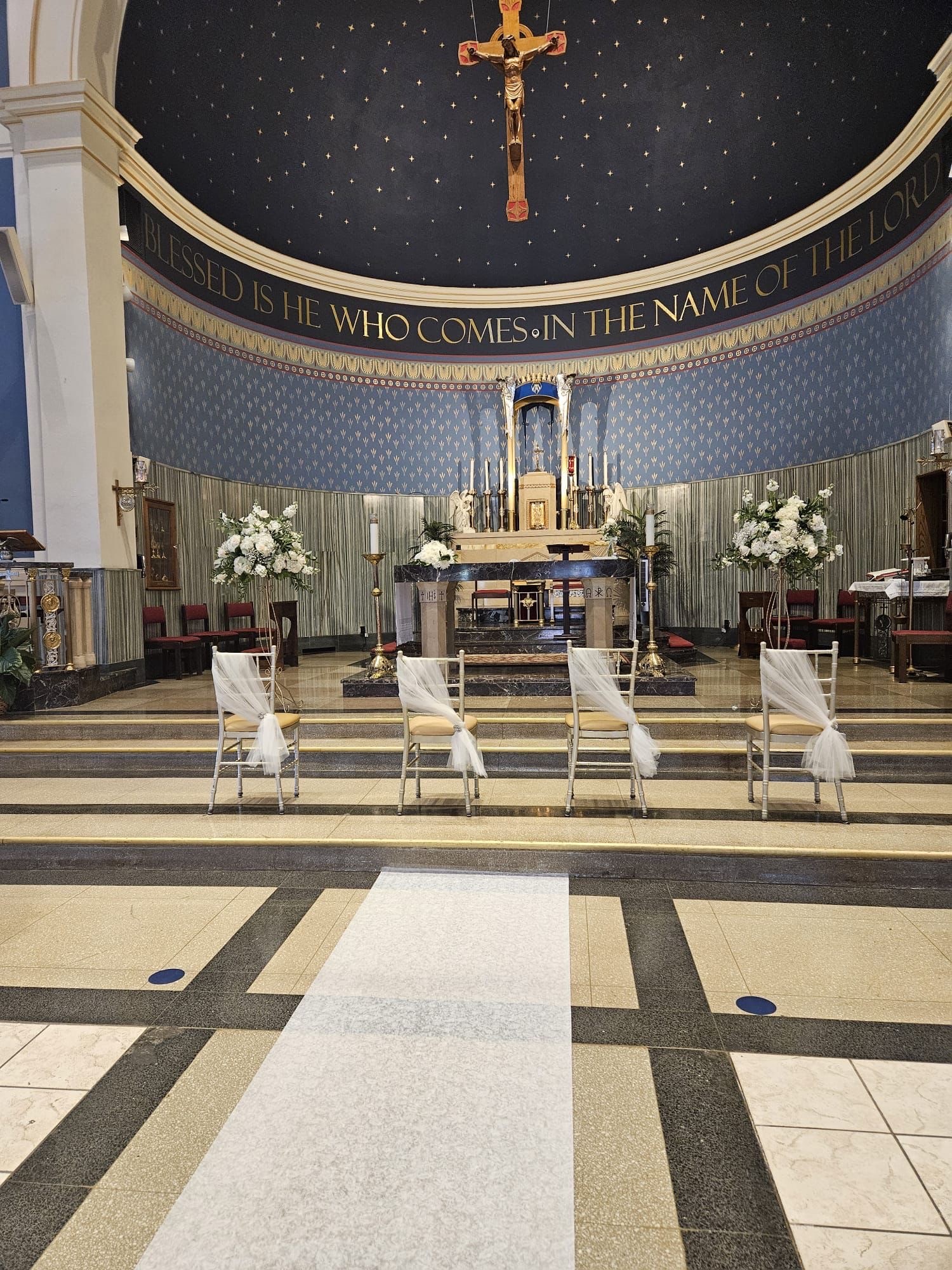 Church sanctuary set for a wedding with tall white altar arrangements and tulle-draped chairs