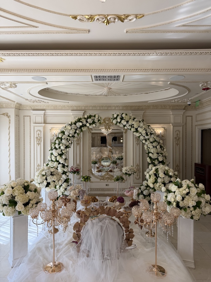 All white hydrangea and rose arch with gold candelabras in an ivory and gold ballroom