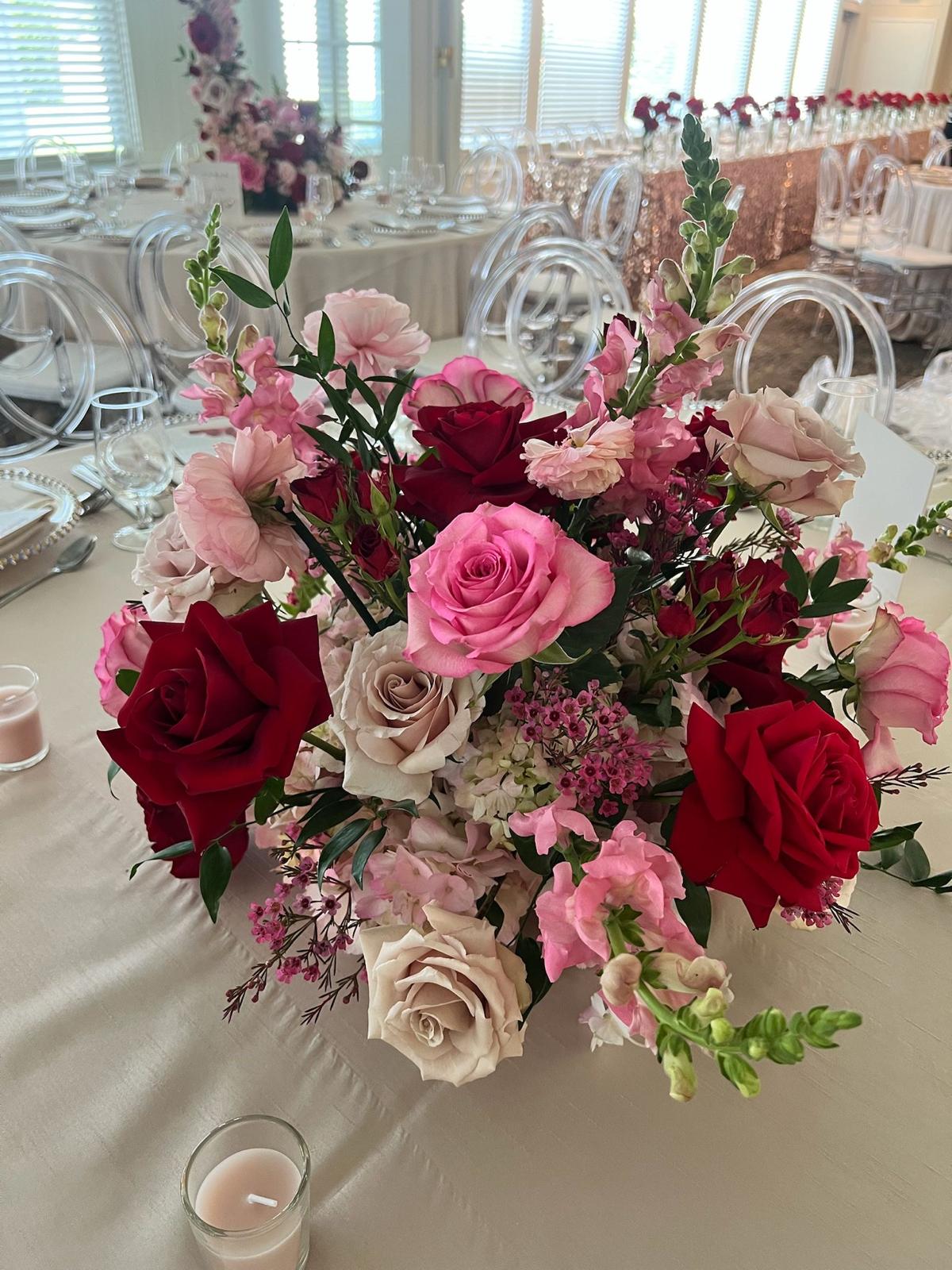 Low garden centerpiece of red, blush and cream roses with snapdragons on an ivory banquet table