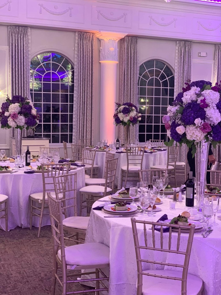 Tall purple, lavender and white hydrangea centerpieces on mirror stands in an elegant ballroom