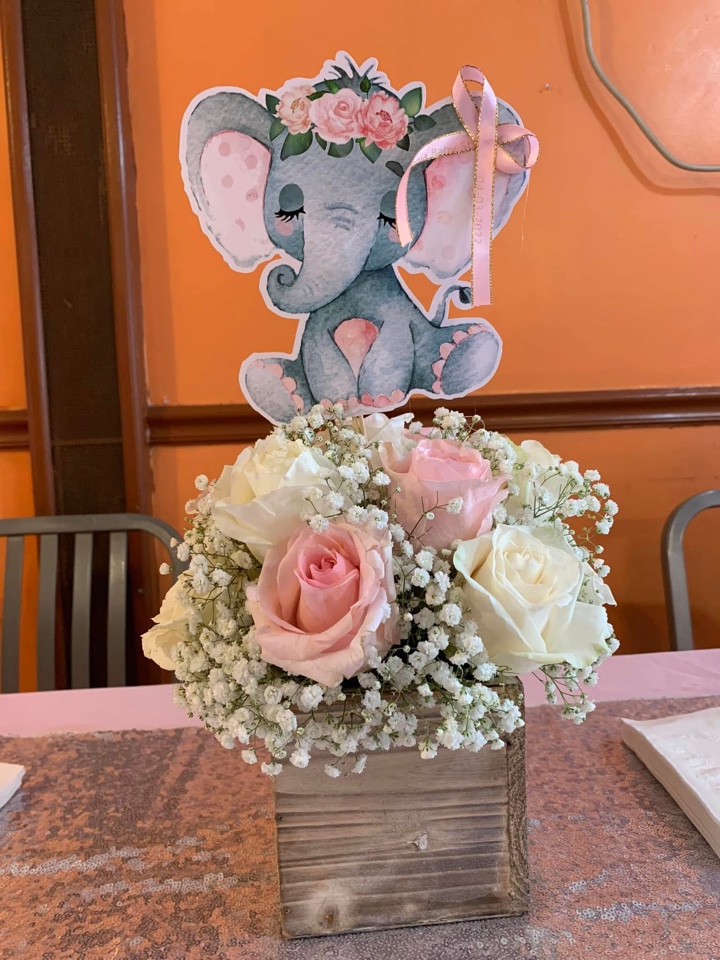 Baby shower centerpiece of pink and white roses with baby's breath in a rustic wood box beneath a watercolor elephant