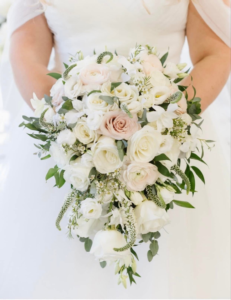 Cascading bridal bouquet of white and blush roses, ranunculus and trailing veronica