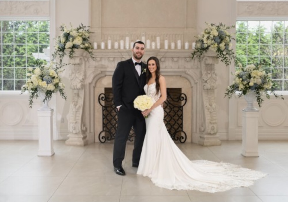Bride and groom beside a fireplace with white and blue urn arrangements on pedestals