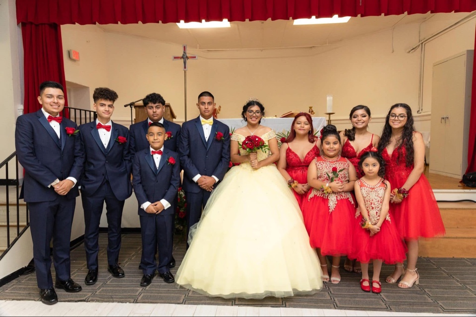 Quinceañera court of honor in navy suits and red dresses with red rose boutonnieres and bouquets