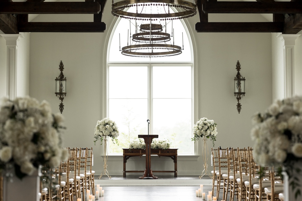 Chapel ceremony with white hydrangea pedestal arrangements, gold chairs and candlelit aisle