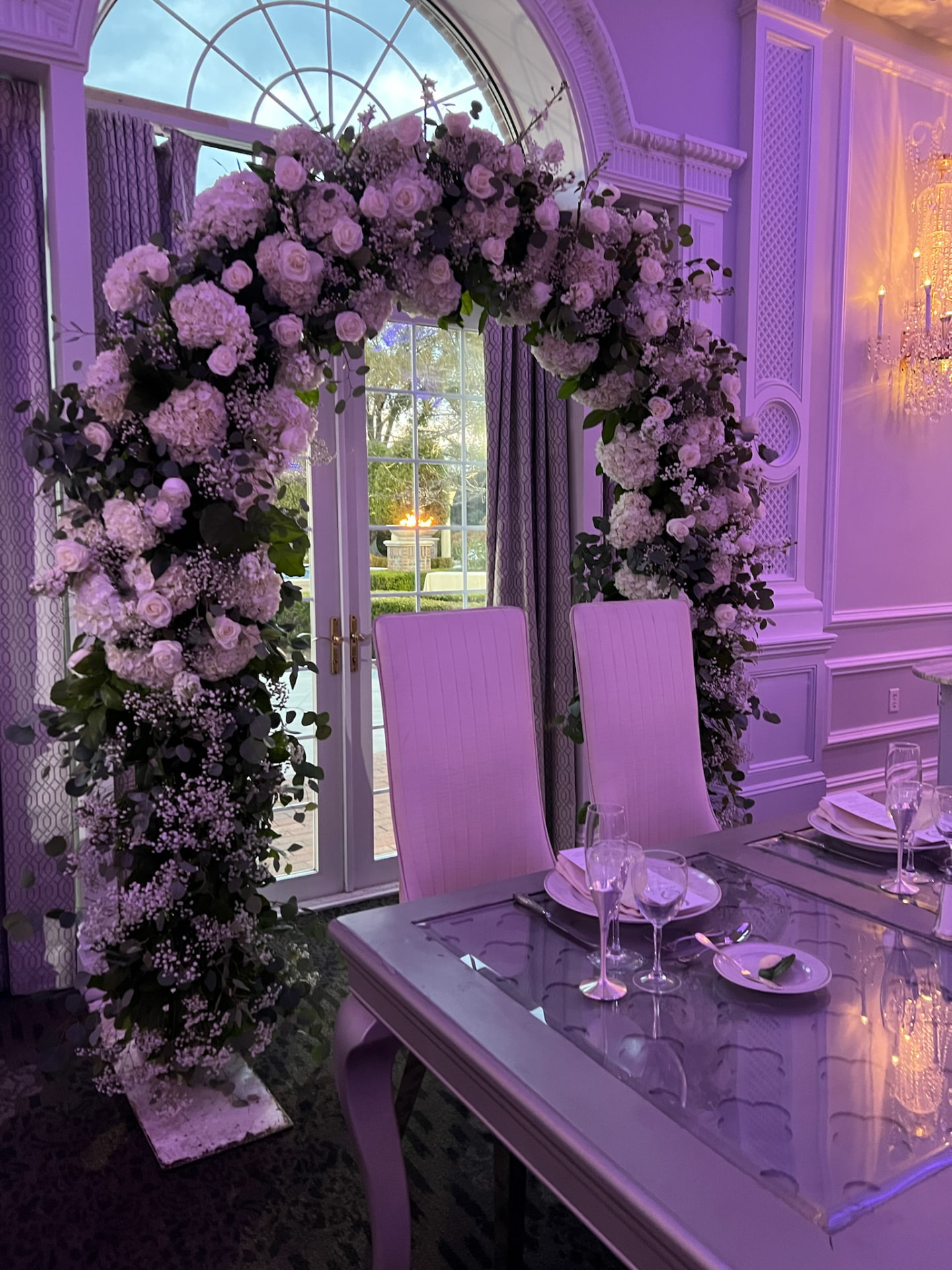 Full blush rose, hydrangea and eucalyptus arch framing french doors behind a sweetheart table