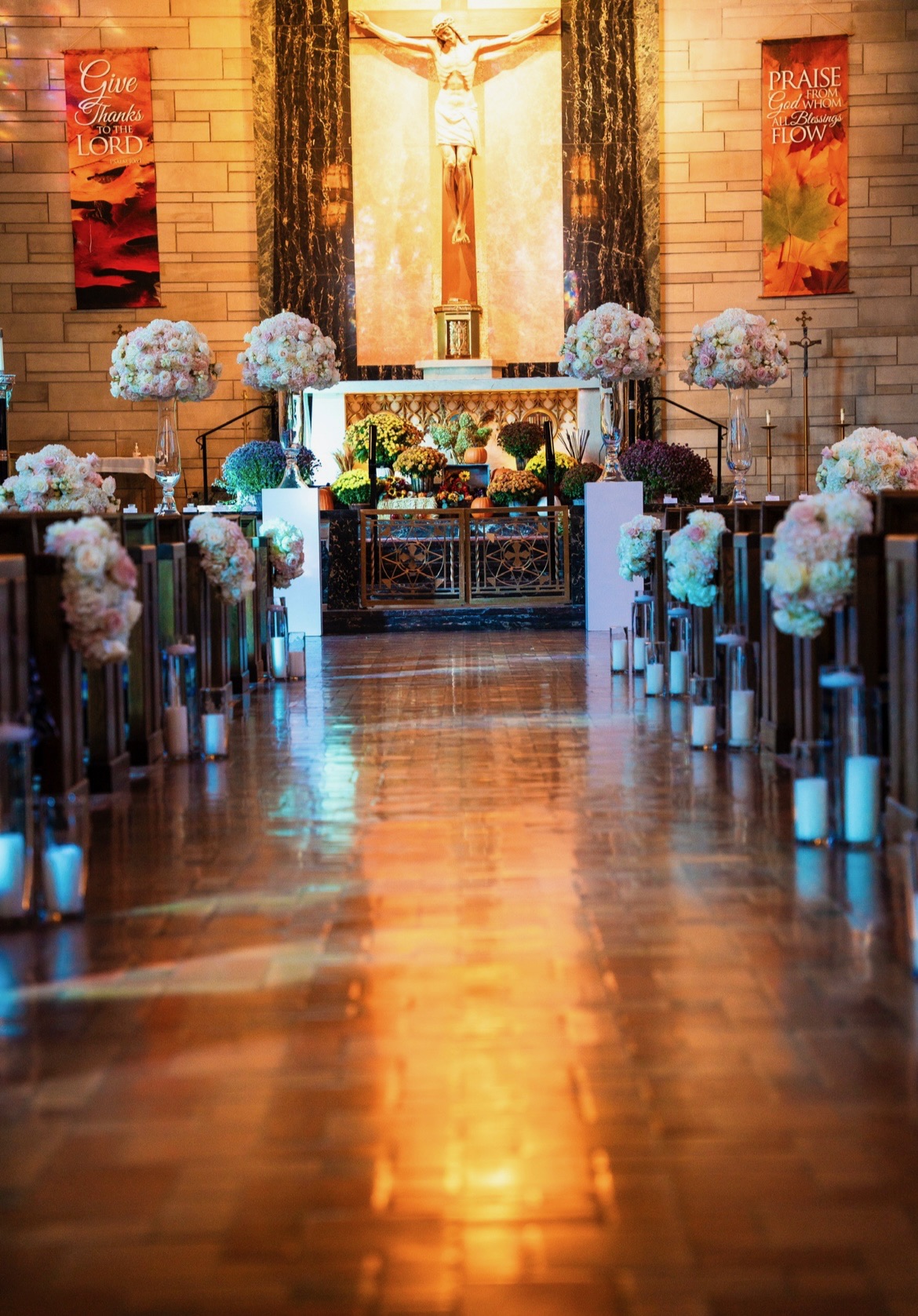 Church altar with tall blush and ivory arrangements on glass stands above an autumn floral display