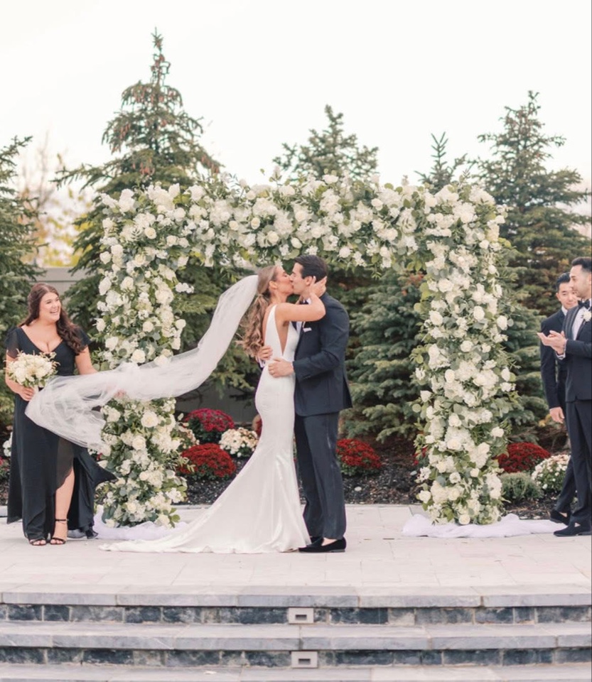 First kiss beneath a square arch of white hydrangea and roses on the terrace