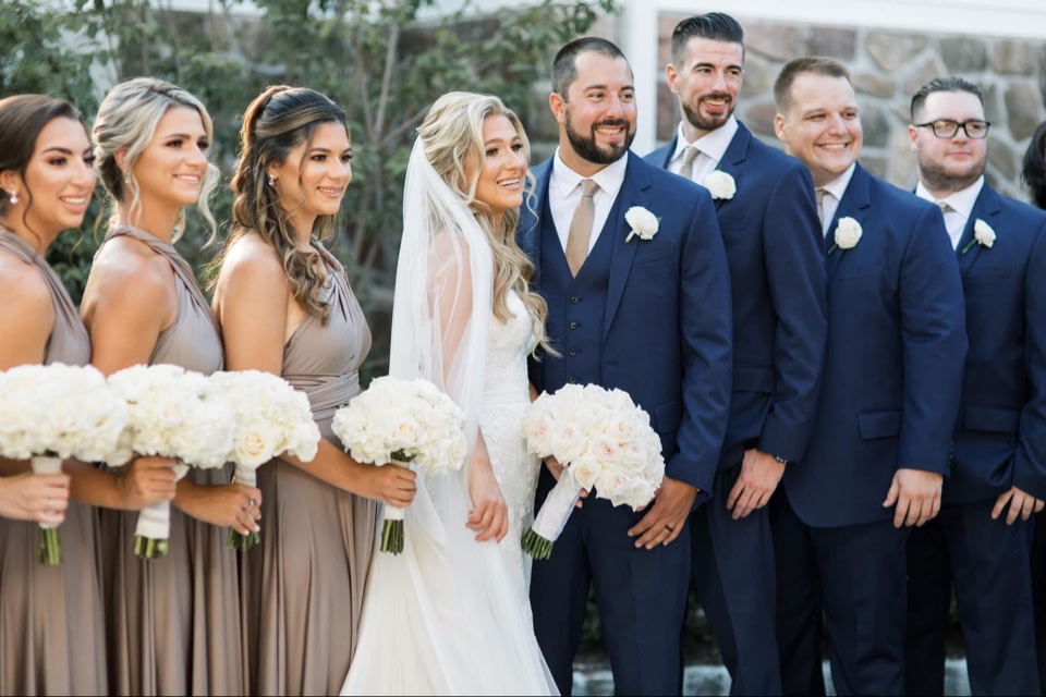 Full wedding party with white bouquets and white rose boutonnieres on navy suits