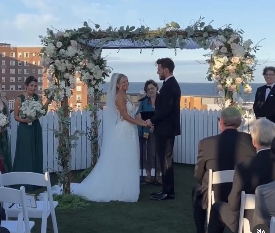 Rooftop ceremony with a birch and greenery chuppah and blush roses overlooking the ocean