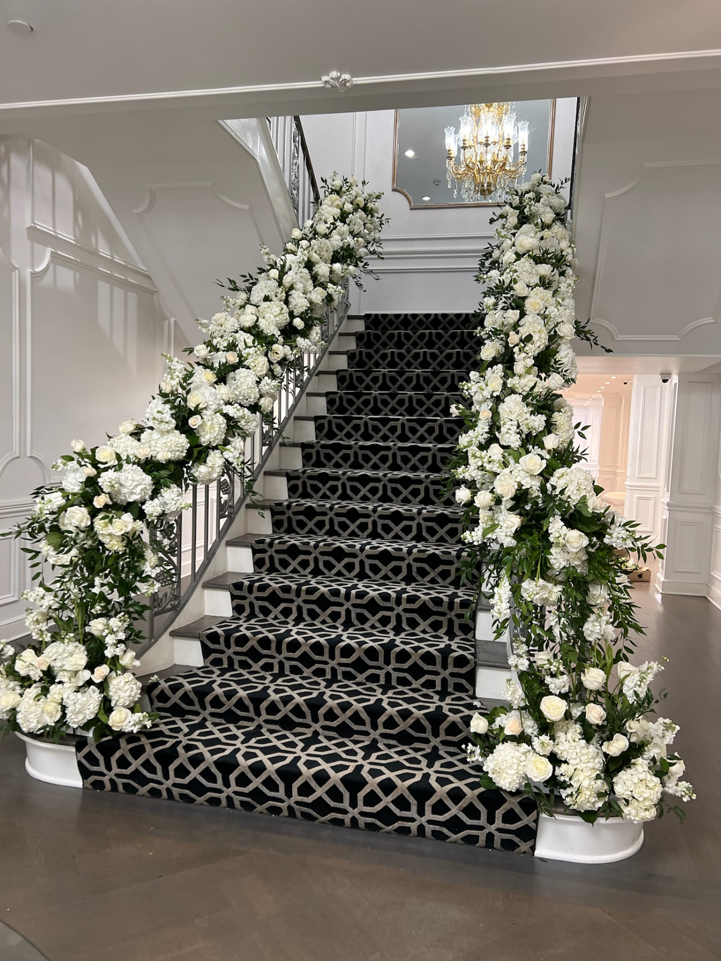 Estate staircase banister covered in white roses, hydrangea and stock with matching floor urns