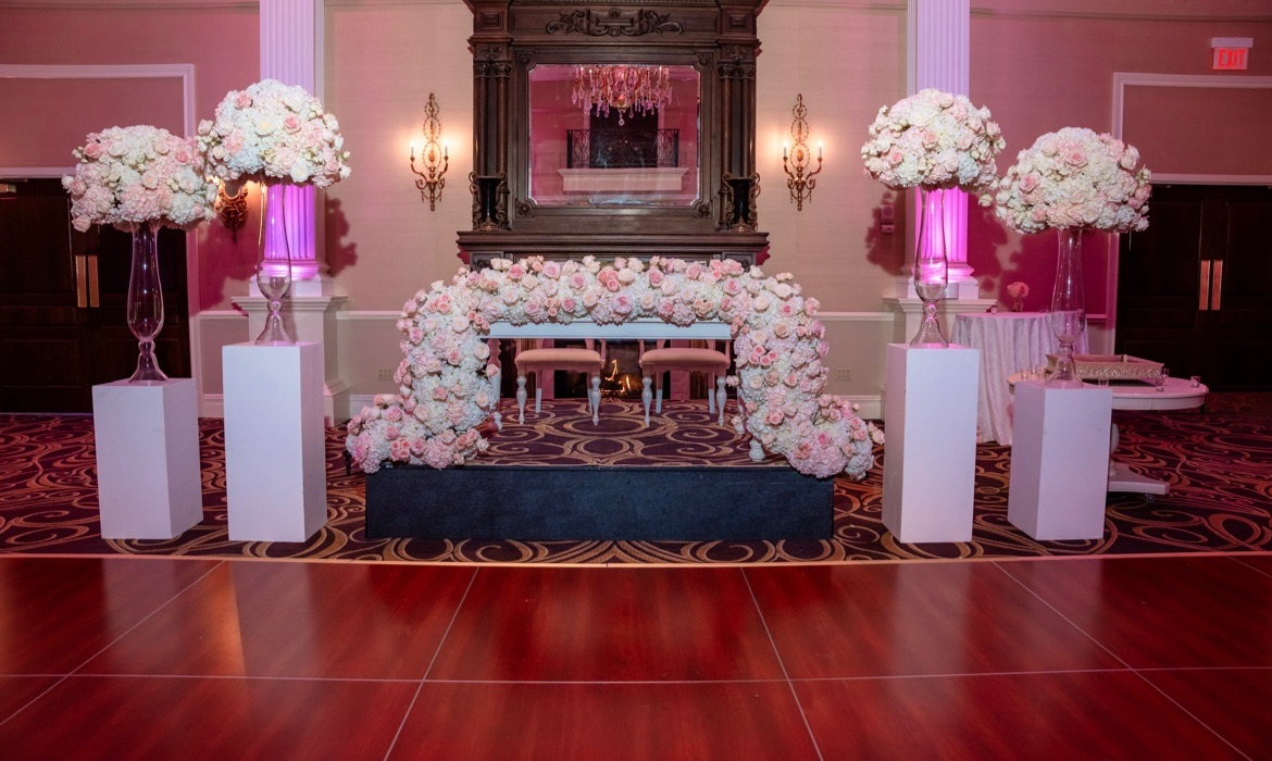 Blush rose sweetheart arch flanked by four pedestal arrangements across a ballroom dance floor