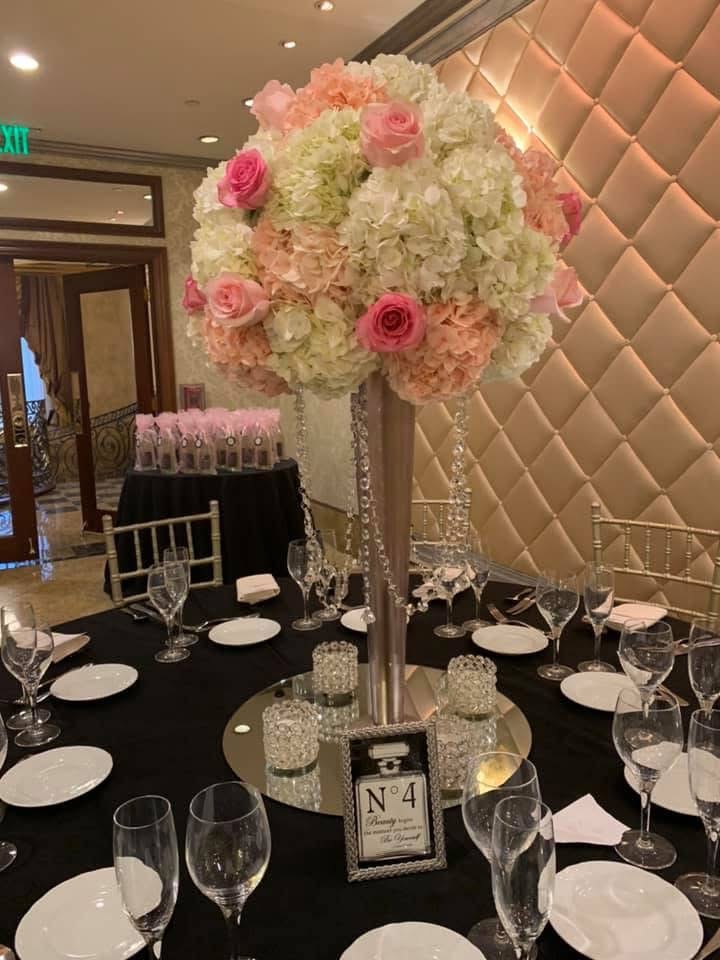Tall cone centerpiece of peach and blush hydrangea with pink roses and hanging crystal strands