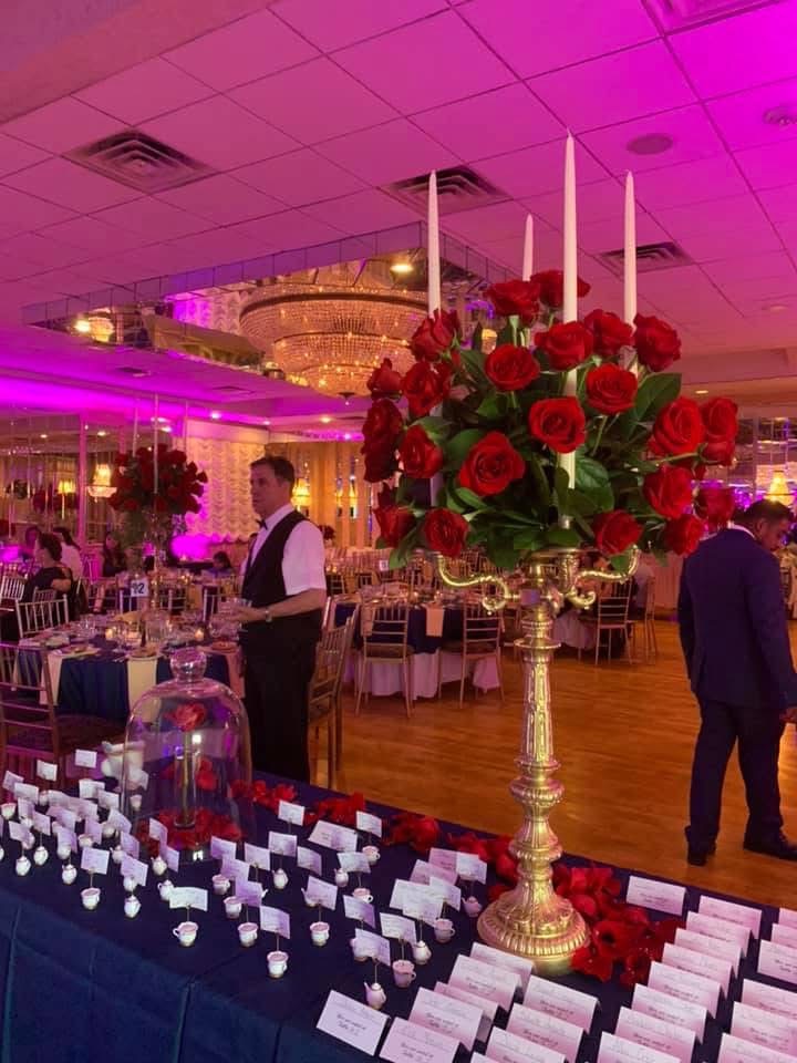 Gold candelabra crowned with red roses and tall tapers on a Beauty and the Beast place card table