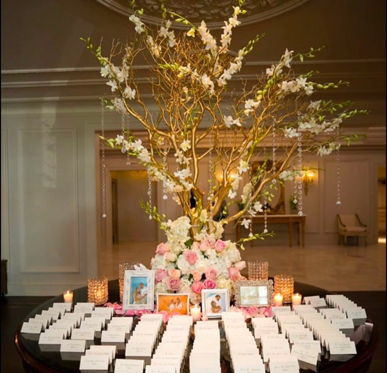 Escort card table with a golden branch tree, white orchids, and blush roses
