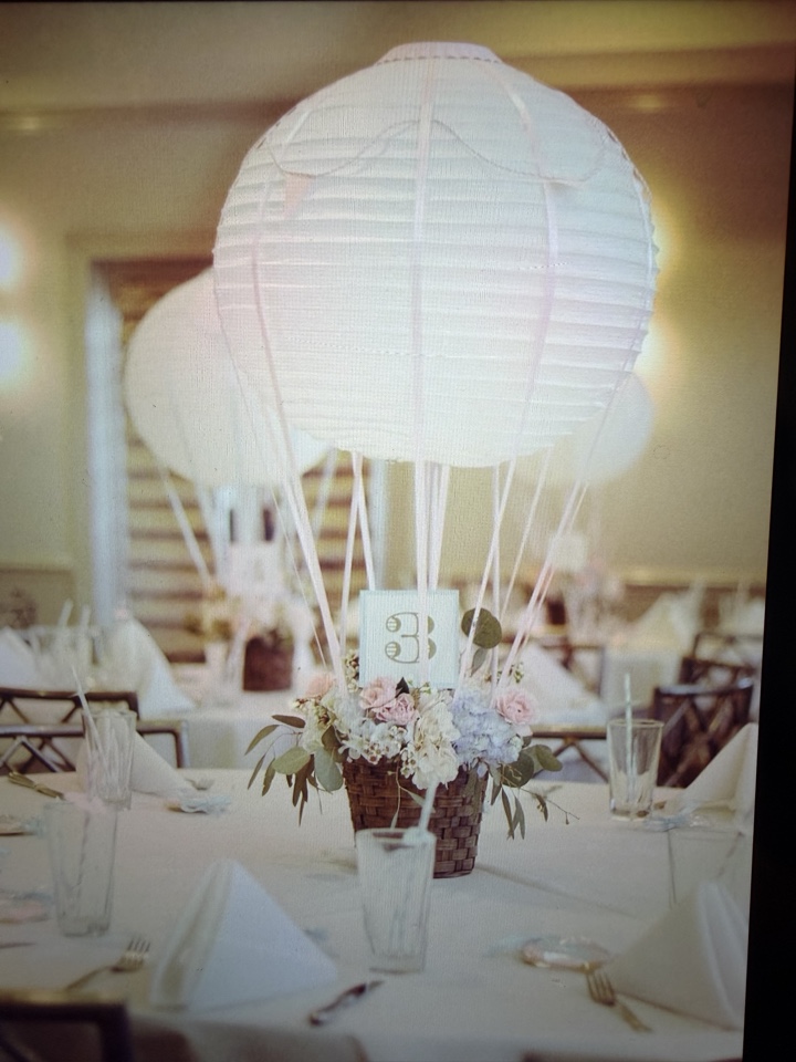 Hot air balloon paper lantern centerpiece floating over a basket of blush and blue garden roses