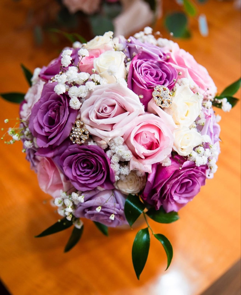 Hand-tied bouquet of purple, lavender and blush roses with baby's breath and jeweled accents