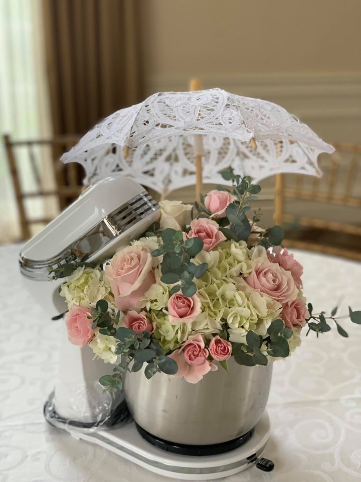 Kitchen mixer bowl brimming with blush roses, white hydrangea and eucalyptus beneath a lace parasol