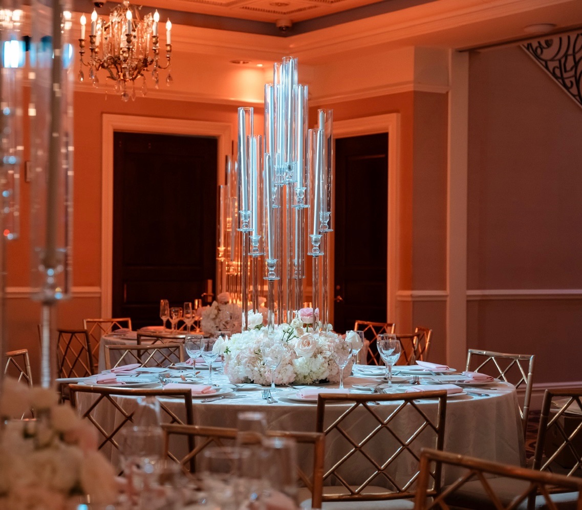 Crystal candelabra towers rising from a white rose and hydrangea base on an amber-lit ballroom table