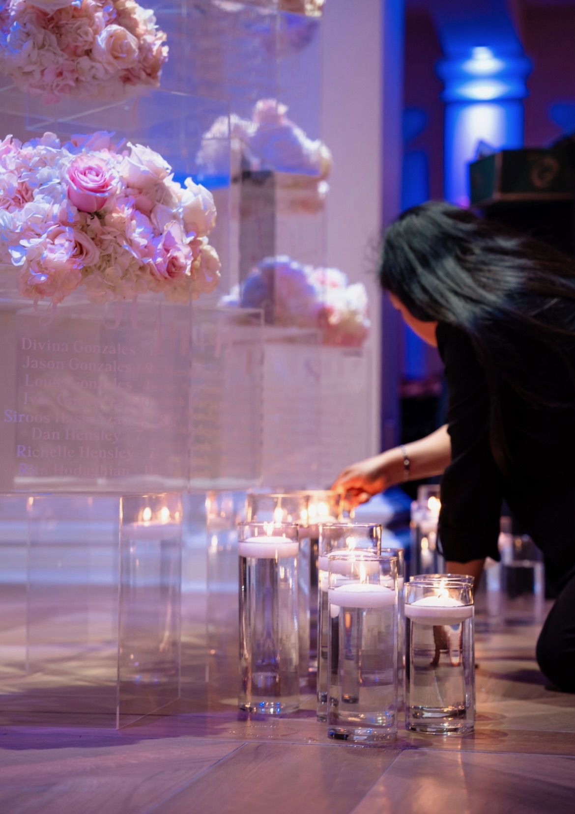 Designer lighting floating candles around an acrylic seating display topped with blush roses