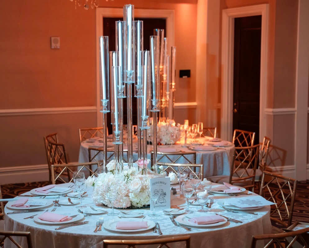 Round reception table with crystal taper candelabra, blush napkins and a low white rose centerpiece