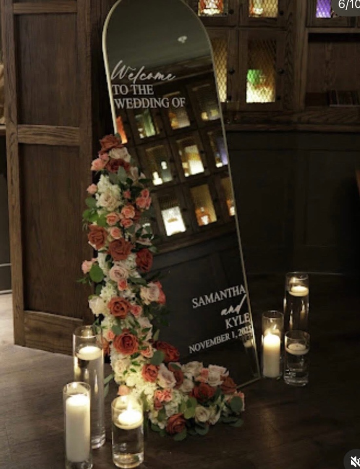 Mirrored welcome sign with a cascading garland of terracotta and blush roses and candles