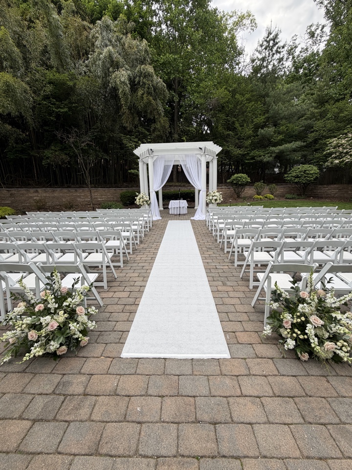 Outdoor gazebo ceremony with blush and white aisle arrangements along a white runner